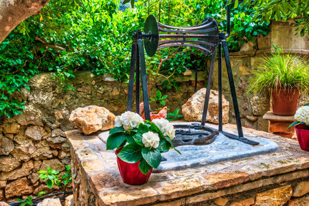 Stone well and flowers inside an orthodox monastery, Attica, Greece.の写真素材