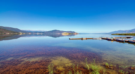 Calm waters of Lake Prespa at Mikrolimni village, reflecting the surrounding mountains with small...