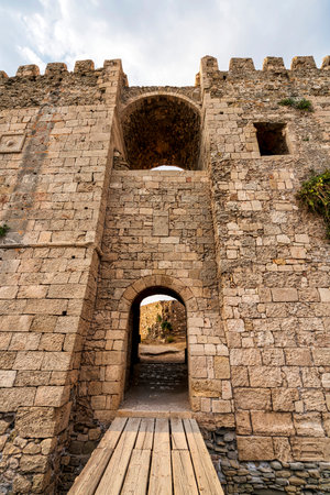 A detailed view of the stone archway and wooden bridge within Methoni Fortress, leading to its...