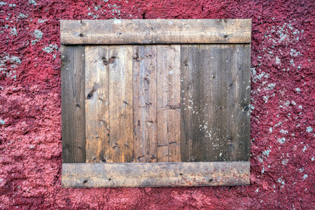 A weathered wooden window shutter on a red-stained wall from the former miners' residences at the...