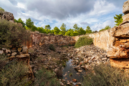 Ruins of an ancient silver mining site in Lavrion, Greece, featuring stone structures, excavation pits, and surrounding green landscape.の写真素材