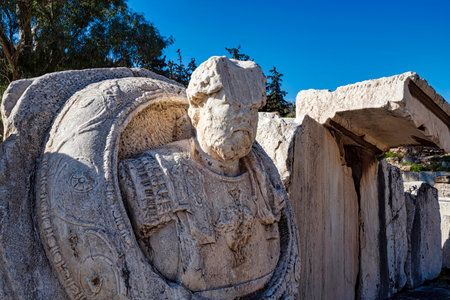 Worn Roman statue in armor at Eleusis, showing detailed cuirass and cloak, symbolizing imperial...