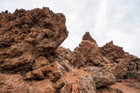 Jagged lava rocks and rugged formations from ancient eruptions dominate the volcanic landscape of Kameno Vouno in Methana, Greece.の写真素材