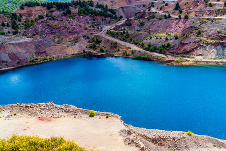 A vivid view of turquoise waters in Triadas Lake surrounded by terraced rocky slopes and sparse...