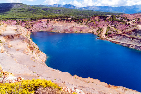 A vivid view of turquoise waters in Triadas Lake surrounded by terraced rocky slopes and sparse...