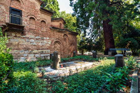 Small cemetery next to Boyana Church in Sofia, Bulgaria, with stone cross, ancient brick walls, and...