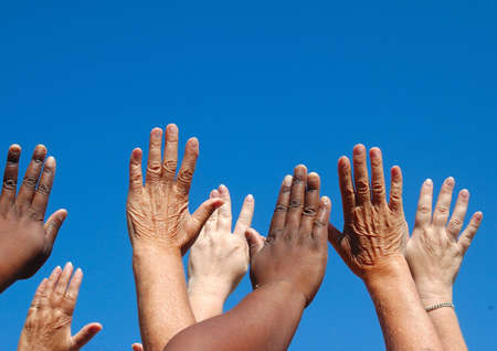 African black and caucasian white hands of four ladies reaching out to the sky symbolizing world freedom for women の写真素材