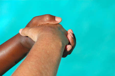 A black hand of an African American woman and a white hand of an caucasian woman shaking, helping and supporting each other の写真素材