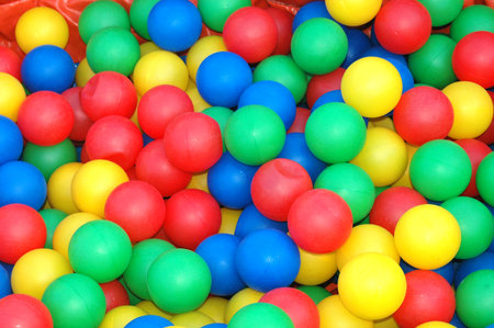 Background closeup of lots of colorful plastic balls in red, yellow, green and blue for kids to play with on the playground outdoors の写真素材