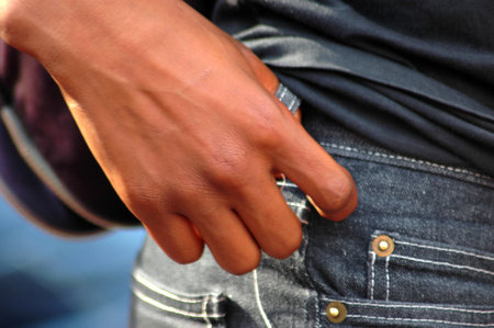 A hand of a young male thief who is stealing money und putting it into his pocket outdoors in the street の写真素材
