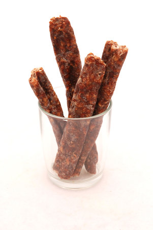 Pieces of African dry wurst in a glass - a traditional and very popular delicious snack made from dried raw meat from South Africa. Image isolated on white background.の写真素材