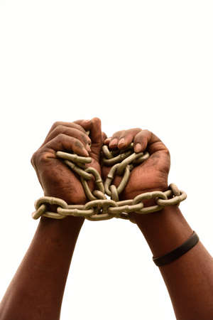 Two chained black male hands of a young South African Xhosa imprisoned man isolated on white studio background.の写真素材