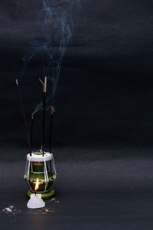 Burnt out incense stick and candle in the dark.の写真素材
