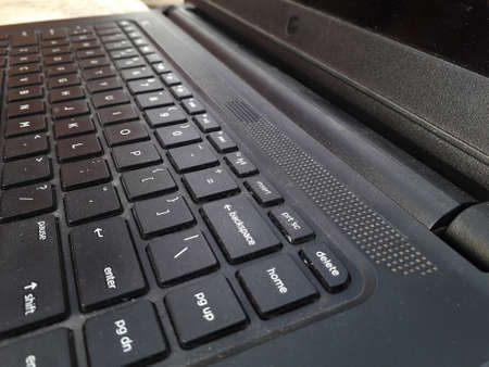 a textured black colored laptop side view near the enter key in keypad