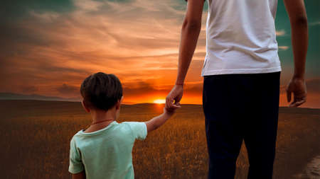 Dad holding daughter's hand looking sunset showing father's dayの写真素材