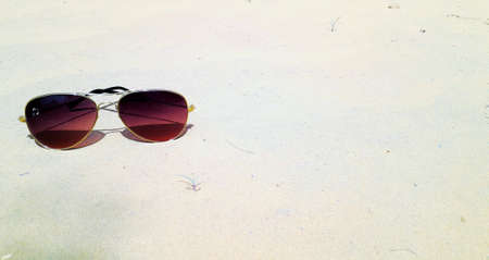 Brown shade sunglasses with golden metallic frame placed on soil in desert with copy spaceの写真素材