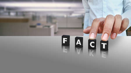 A male person putting cubes labeled with FACT text and FAKE in reflection conceptual image on Social...
