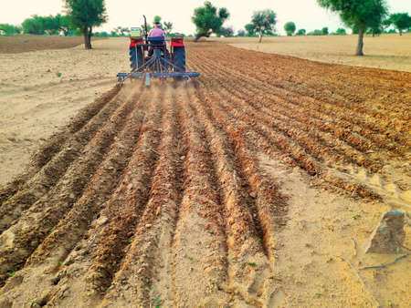 tractor cultivating agriculture land to grow crop in desert area of India