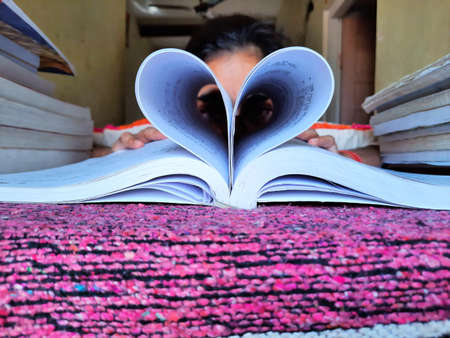 girl making heart shape of book pages and showing love on book lovers dayの写真素材