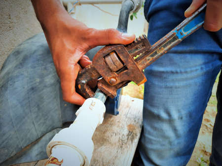 Plumber repairing water fitting with adjustable wrenchの写真素材