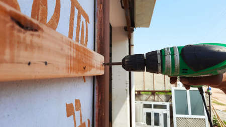 Tightening screw in wall with electric screw tighter machine