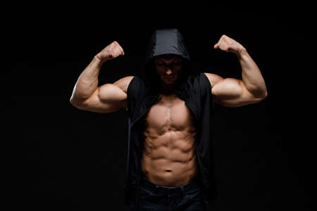 Muscular bodybuilder on a black background. Sports nutrition. Bodybuilding nutrition supplements, workout, healthy lifestyle concept.の写真素材