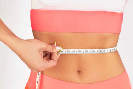 Girl the brunette costs measures her hips with a measuring tapeの写真素材