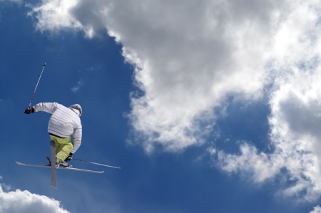 Freestyle ski jumper with crossed skis against blue sky with clouds Freestyle ski jumper with crossed skis against blue sky with clouds