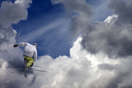 Freestyle ski jumper with crossed skis against blue sky with cloudsの写真素材