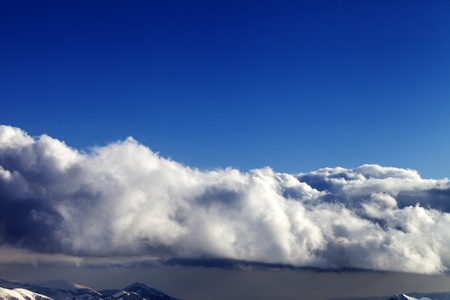 Blue sky and winter mountains covered with clouds