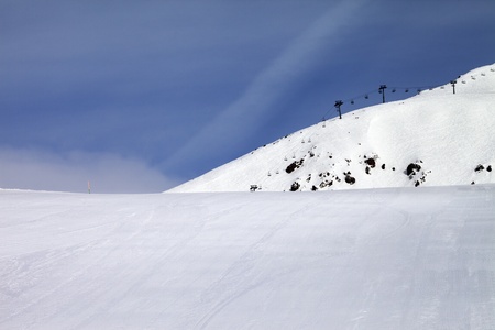 Ski slope and chair-lift against blue sky. Georgia, ski resort Gudauri. Caucasus Mountains.の写真素材