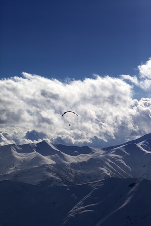 Winter mountain in evening and silhouette of parachutist. Caucasus Mountains. Georgia, ski resort...
