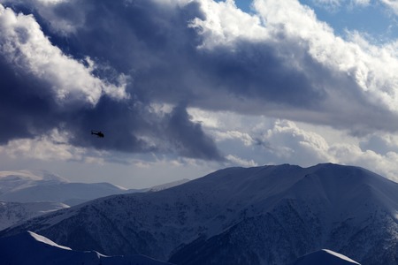 Helicopter in winter mountains and cloudy sky in evening. Ski resort Gudauri. Caucasus Mountains, Georgia.のeditorial素材