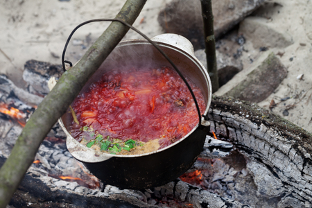 Borscht (Ukrainian traditional soup) cooking in sooty cauldron on campfire at forestの写真素材