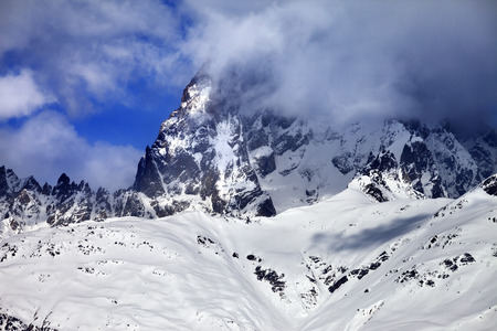 Mount Ushba in fog at sun winter day before storm. Caucasus Mountains. Svaneti region of Georgia.