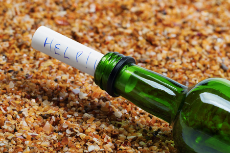 Bottle of wine with help message on sand in beach at sun summer day. Close-up view.の写真素材