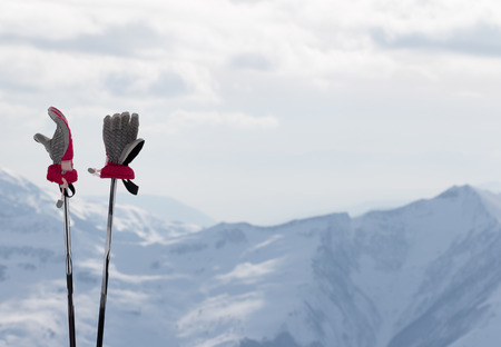 Ladies gloves on ski poles and snow winter mountains in background. Caucasus Mountains. Georgia, region Gudauri.の写真素材