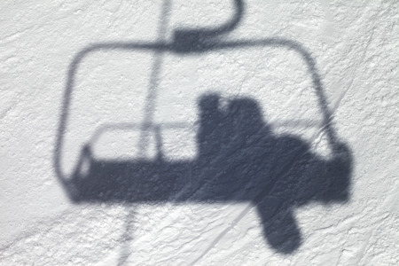 Shadows from chair lift with snowboarder on off-piste slope in sun winter dayの写真素材