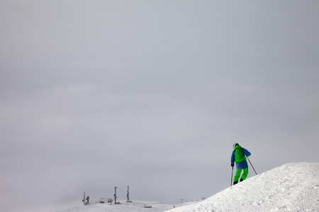Skier before downhill on snowy freeride slope and overcast misty sky at day with bad weather. Caucasus Mountains in winter, Georgia, region Gudauri.の写真素材