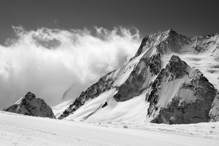 Black and white view on snowy sunlight mountains in clouds. Caucasus Mountains. Region Dombay in winter.の写真素材