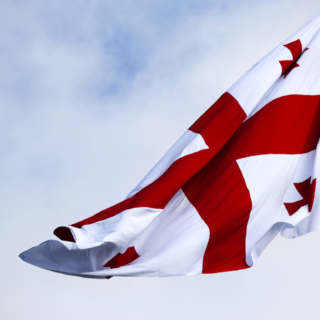 Waving on wind flag of Georgia and cloudy sky at windy day. Close-up view.の写真素材