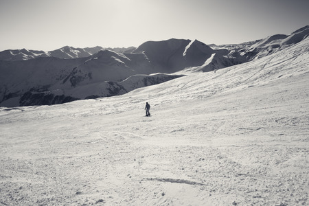 Skier on snowy slope in sun winter day. Caucasus Mountains, Georgia, region Gudauri. Black and white...