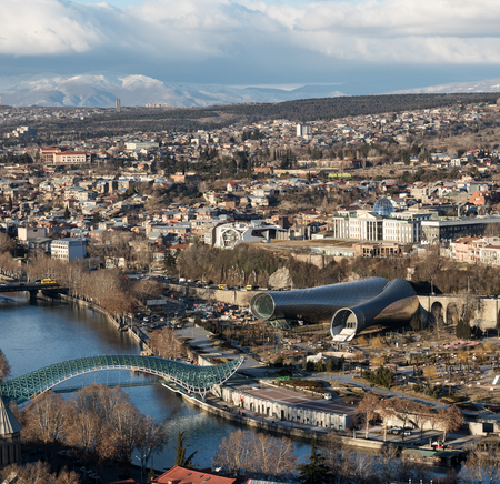 Center of Tbilisi, capital of Georgia on sunny day. View on Rike park, modern Concert Hall, Presidential Administration, Kura river, Bridge of Peace and mountains in clouds at background.の写真素材