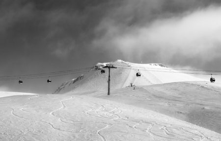 Black and white view on gondola lift and off-piste ski slope in fog at nice sunny evening. Caucasus Mountains in winter, Georgia, region Gudauri, mount Kudebi.の写真素材