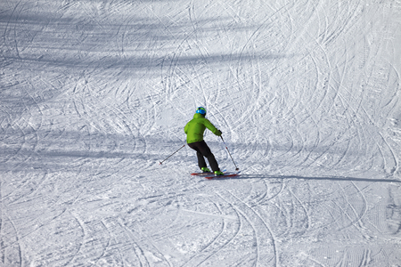 Skier descent on snowy ski slope with curves from skis at sunny winter day. Caucasus Mountains. Hatsvali, Svaneti region of Georgia.の写真素材