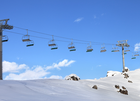 Sunlight chair-lift and blue sky with clouds at ski resort on sun cold evening. Caucasus Mountains in winter, Shahdagh, Azerbaijan.の写真素材