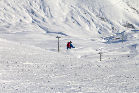 Skier descends on snowy ski slope in sun winter evening. Caucasus Mountains, Georgia, region Gudauri.の写真素材