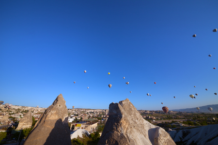 Multicolor hot air balloons on blue clear sunlight sky and fairy chimneys rock formations at early morning. Wide-angle view.の写真素材