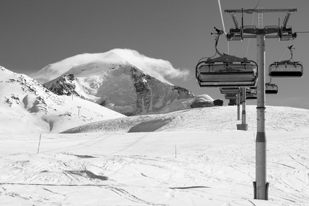 Ski-lift and ski slope in snowy mountains at sunny winter day. Caucasus Mountains. Mount Tetnuldi, Svaneti region of Georgia. Black and white toned landscape.の写真素材