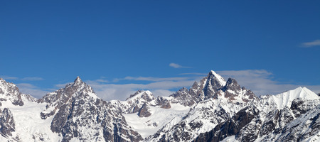 Panoramic view on rocky peaks of mountains in snow and beautiful blue sky at sun winter day. Caucasus Mountains, Svaneti region of Georgia.の写真素材